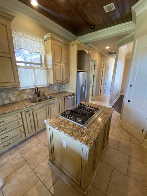A kitchen with a granite countertop and a stove top oven.