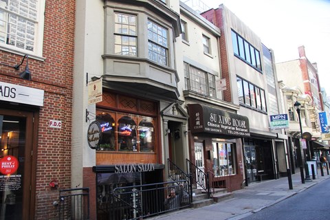 a city street with buildings and a clock on the side of a building