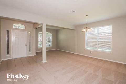 A spacious room with a carpeted floor and a chandelier hanging from the ceiling.