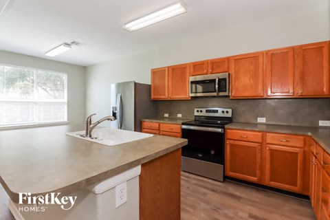 A kitchen with orange cabinets and a stainless steel oven.