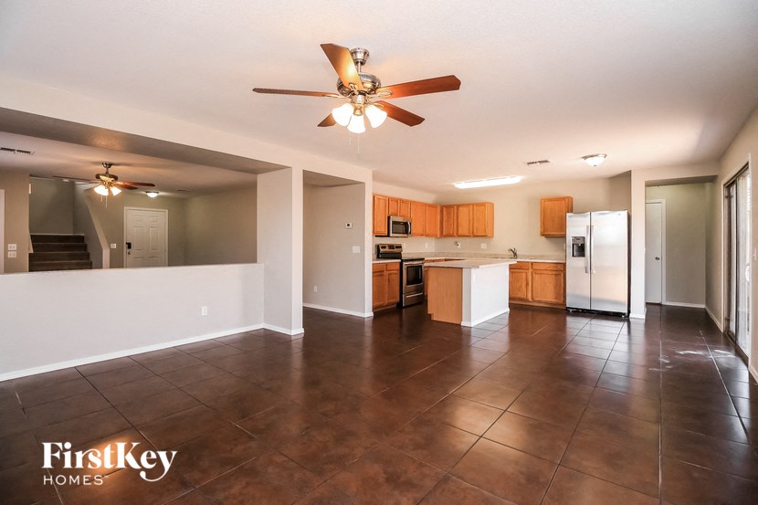 an empty kitchen with a ceiling fan and a refrigerator