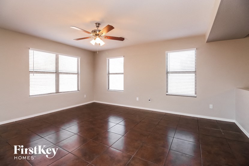a empty living room with a ceiling fan and windows