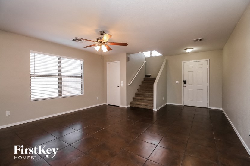 an empty living room with a ceiling fan and a staircase