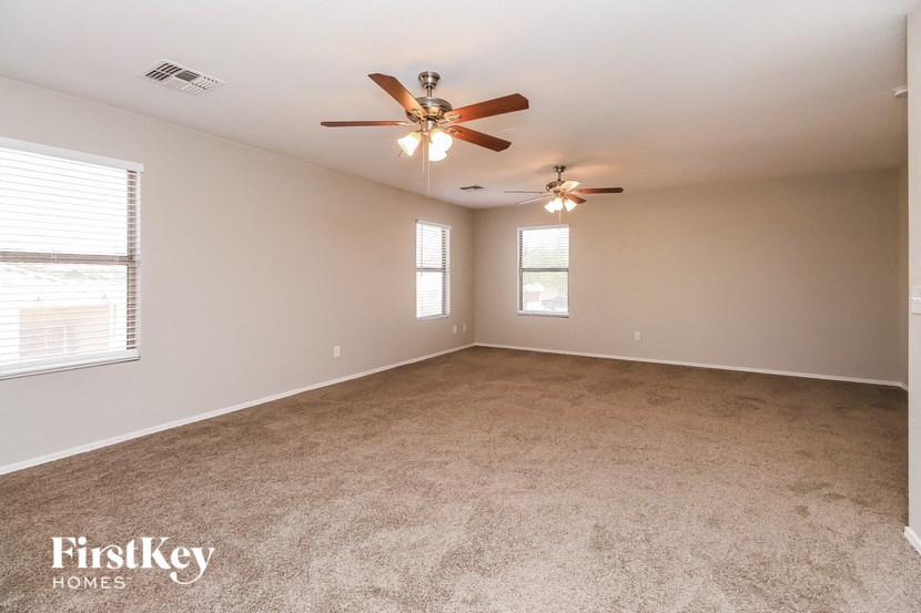 an empty living room with a ceiling fan and a window
