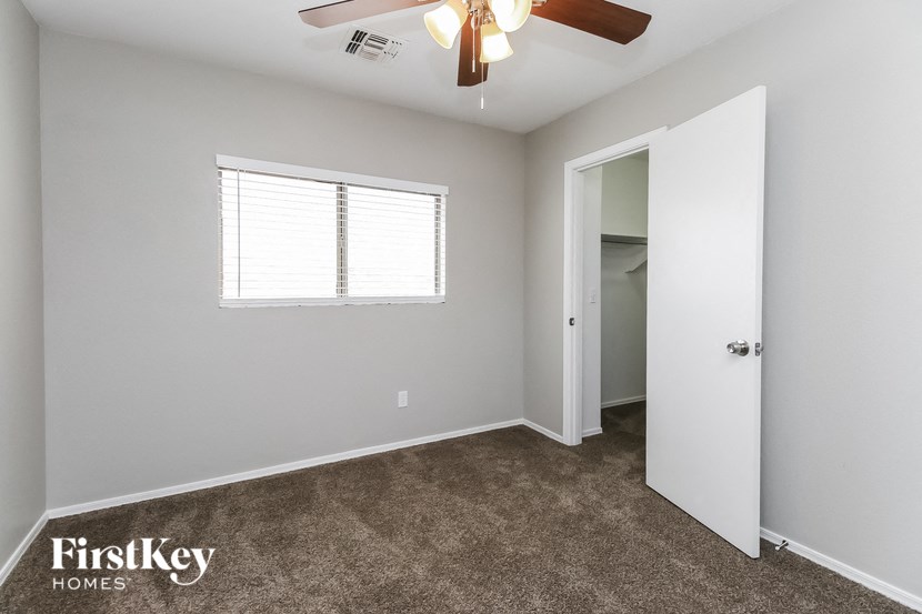 a bedroom with a ceiling fan and a door to a closet