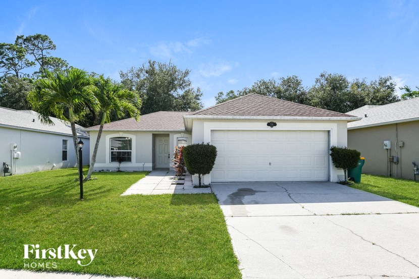 a white house with a driveway and a palm tree