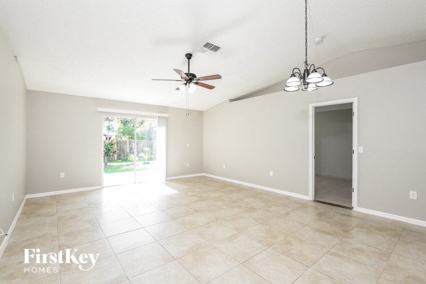 an empty living room with a ceiling fan and a door to a patio
