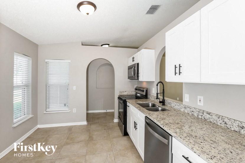 a kitchen with white cabinets and granite counter tops and a sink