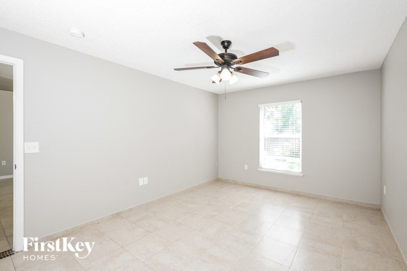an empty room with a ceiling fan and tiled floors