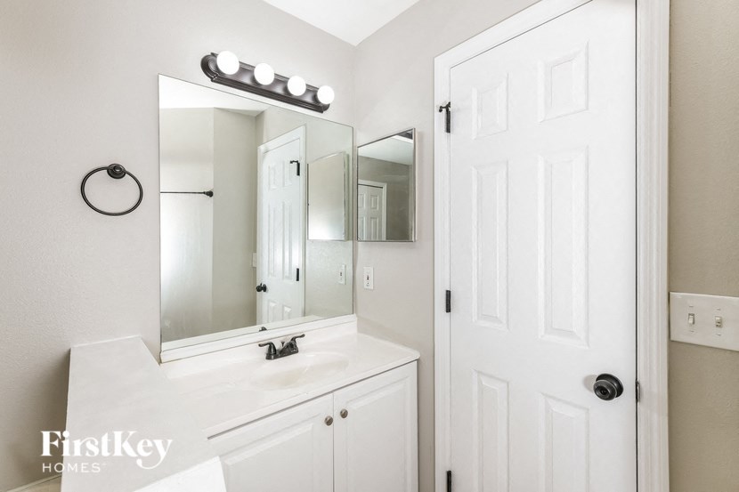 a white bathroom with a white sink and mirror