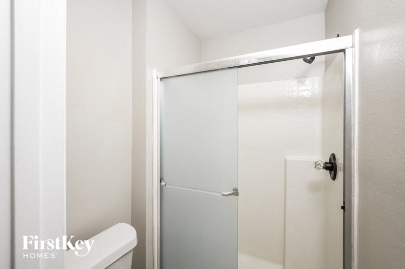 a walk in shower with a sliding glass door in a white bathroom