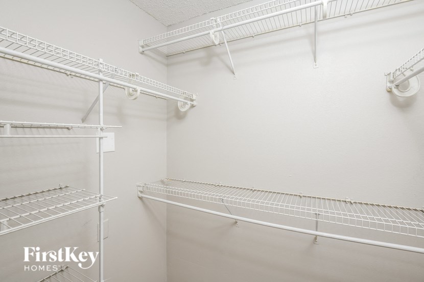 a spacious walk in closet with white walls and white shelves and racks