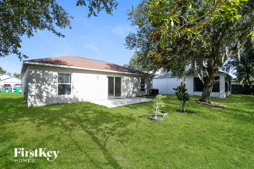a backyard with a white house and a tree