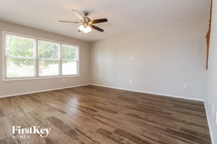 an empty living room with wood flooring and a ceiling fan