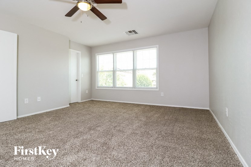 an empty living room with a ceiling fan and a window