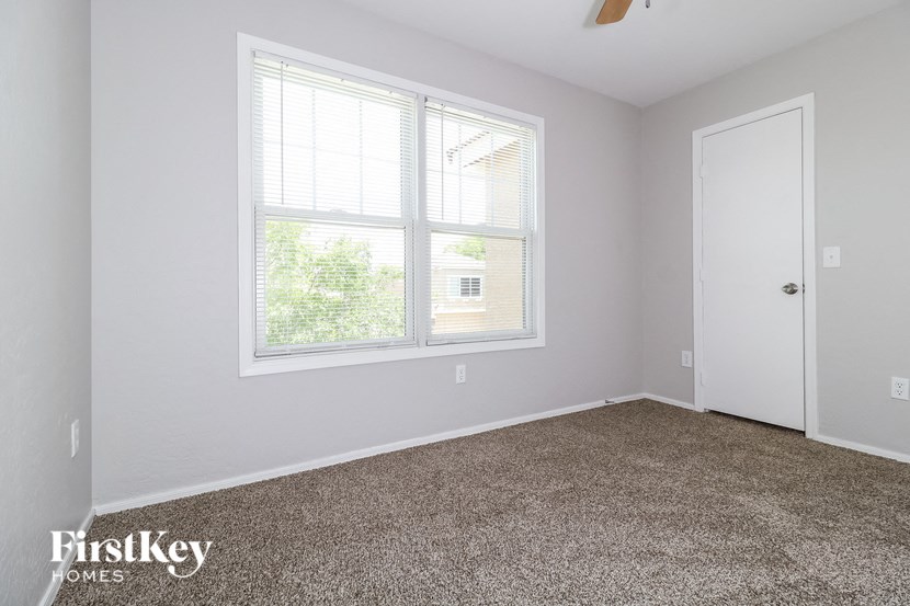 a bedroom with a large window and a carpeted floor