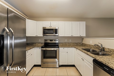 a kitchen with white cabinets and granite counter tops and stainless steel appliances