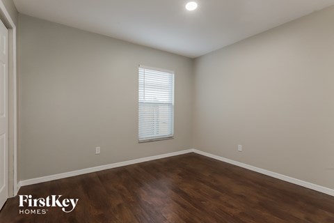 the upstairs bedroom with hardwood flooring and a window