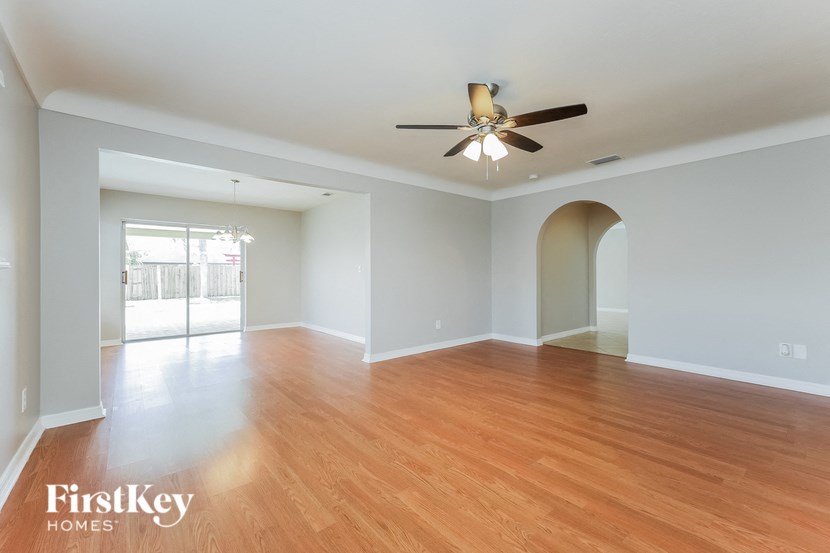 an empty living room with wood flooring and a ceiling fan