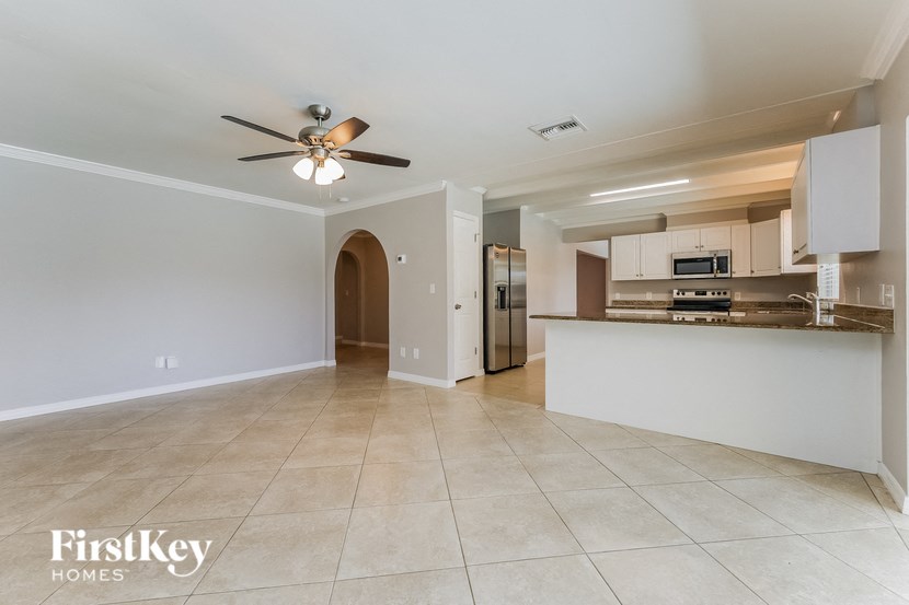 an empty living room and kitchen with a ceiling fan