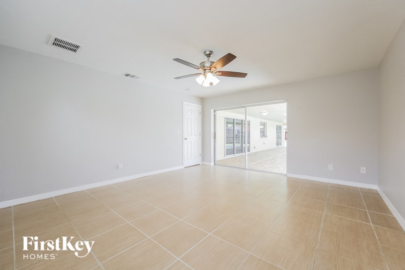 an empty living room with a ceiling fan and tiled floors