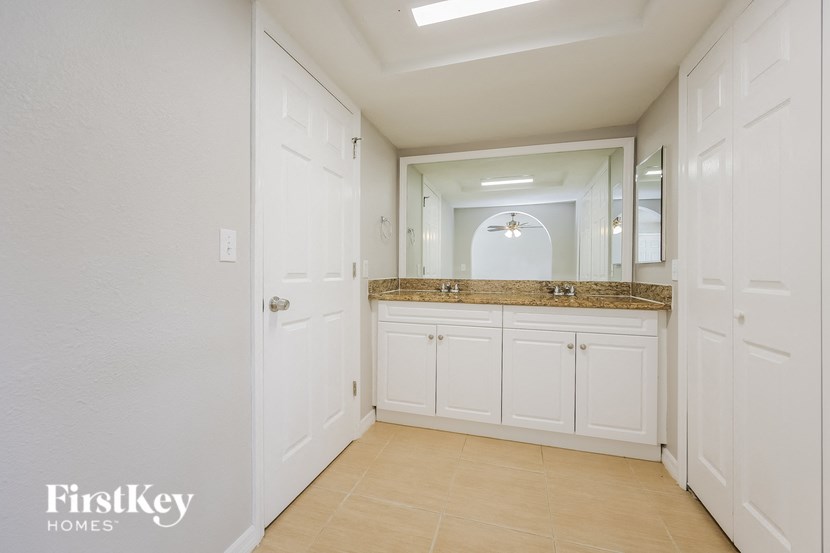 a bathroom with white cabinets and a sink and a mirror