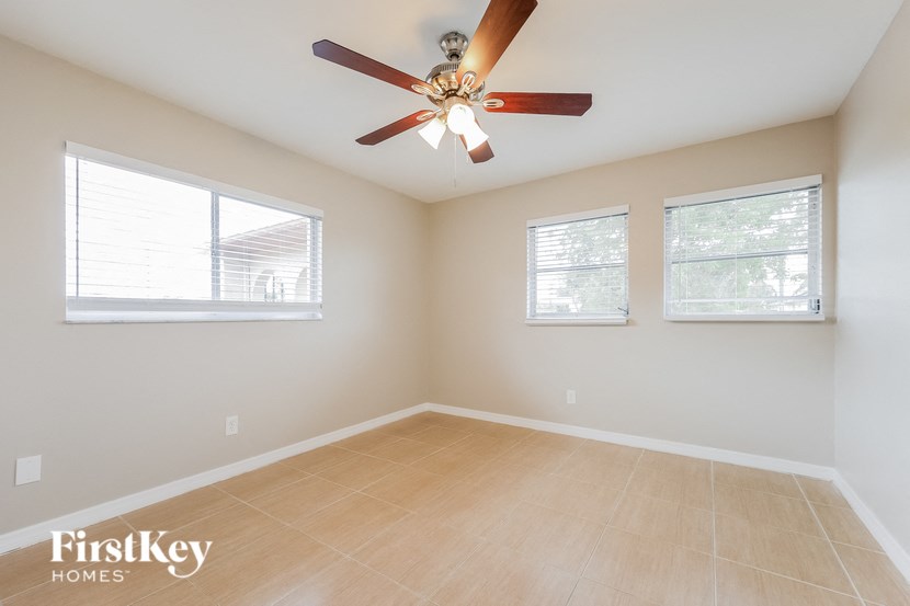 an empty room with a ceiling fan and two windows