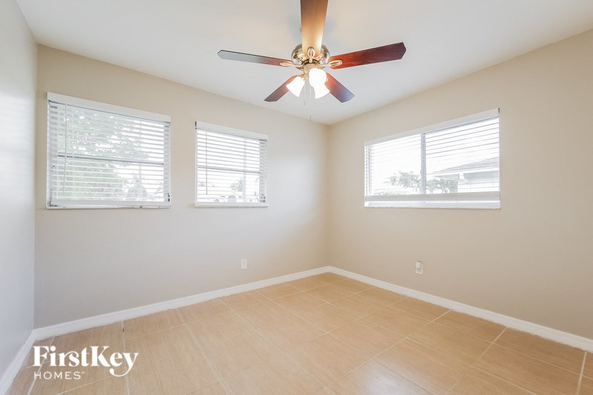 an empty room with a ceiling fan and two windows
