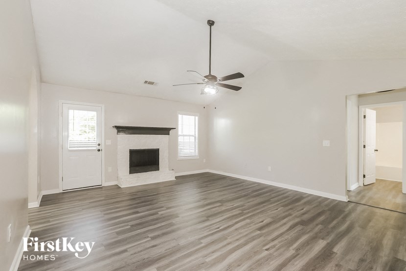 an empty living room with a fireplace and a ceiling fan