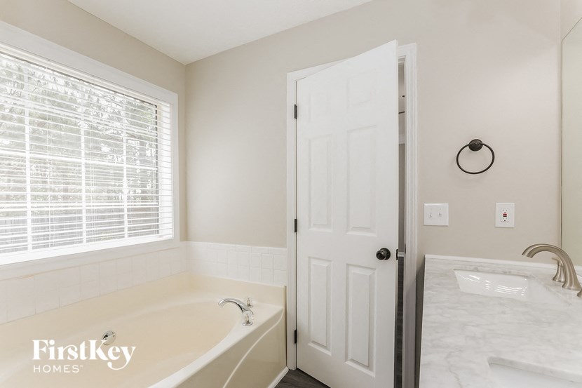 a white bathroom with a tub and a window