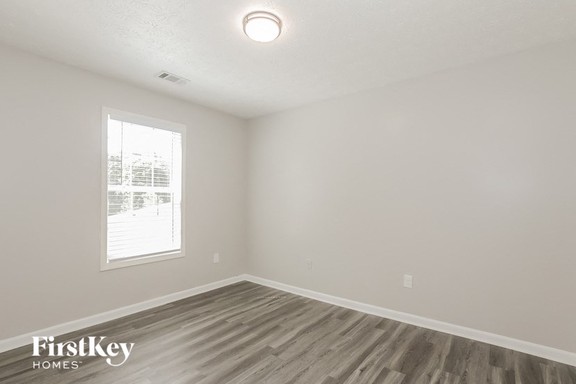 an empty living room with wood flooring and a window