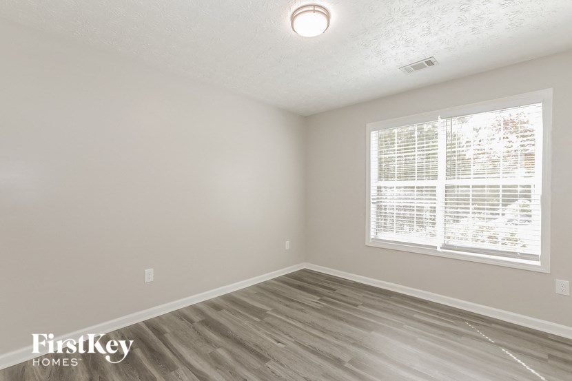 an empty bedroom with a large window and wood flooring
