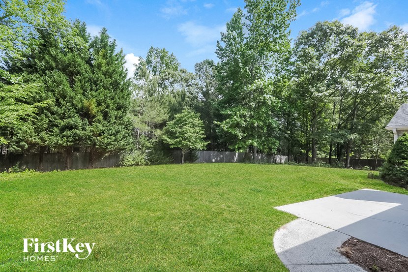 a backyard with a lawn and a fence and trees