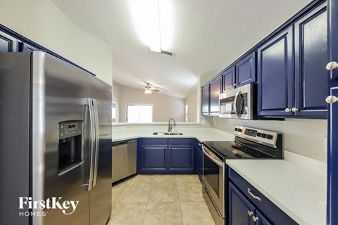 A kitchen with blue cabinets and a stainless steel refrigerator.
