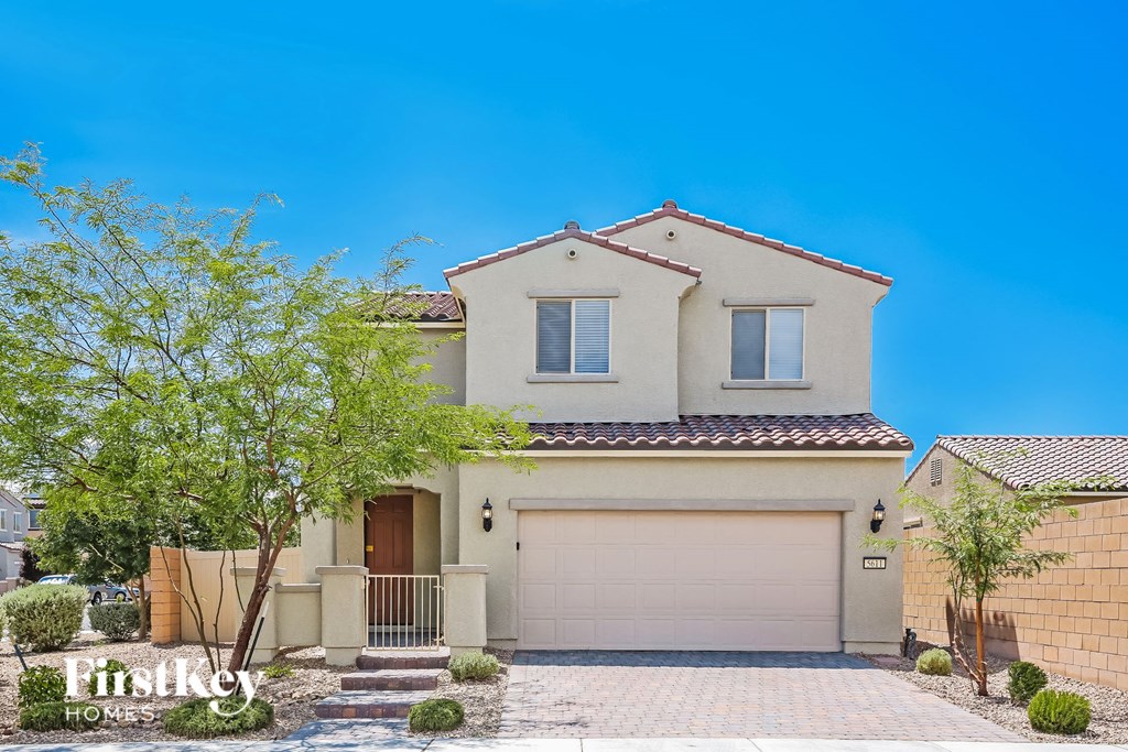 a beige house with a garage door and a tree