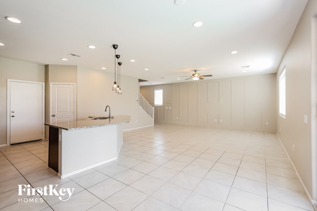 an empty kitchen and living room with white tile flooring and white cabinets