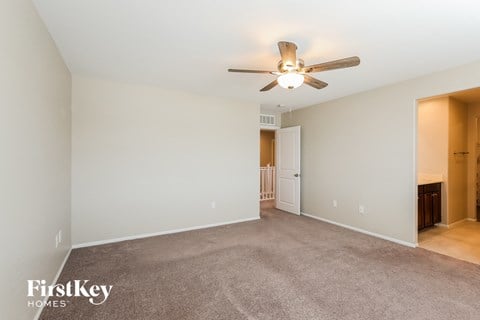 a spacious living room with carpet and a ceiling fan