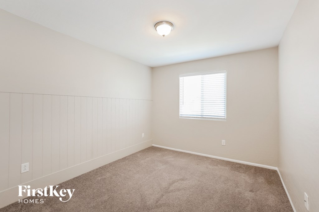 a bedroom with white walls and carpet and a window