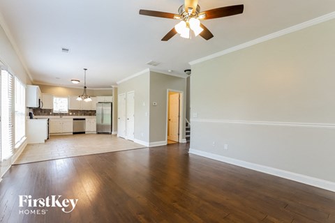 A spacious living room with a ceiling fan and hardwood floors.