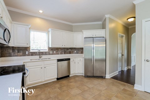 A kitchen with white cabinets and a tile backsplash.