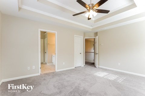 A spacious room with a ceiling fan and a carpeted floor.