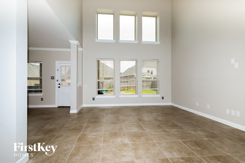 a large empty living room with windows and tile flooring