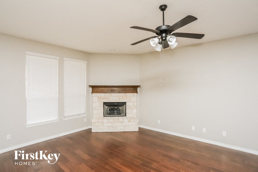 A spacious room with a fireplace and a ceiling fan.