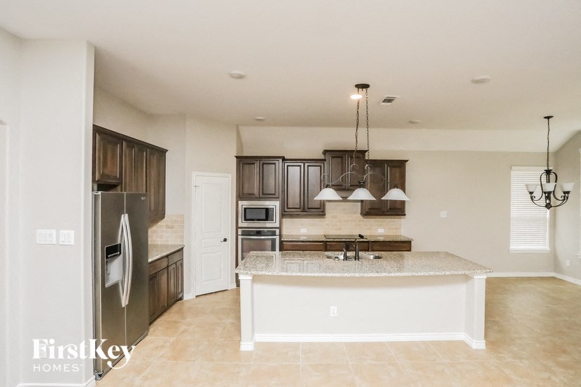 A kitchen with a refrigerator, sink, and cabinets.