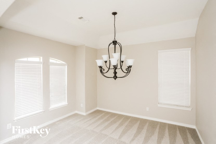 A well-lit room with a chandelier and two windows.