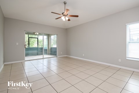 A spacious room with a ceiling fan and sliding glass doors leading to a garden.
