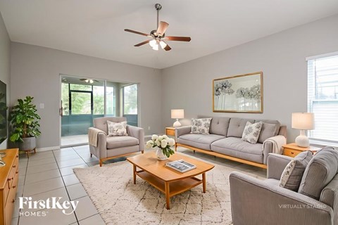 A living room with a grey couch, a coffee table, and a ceiling fan.