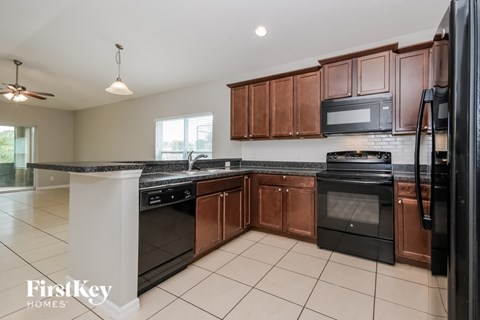 A kitchen with a black fridge and stove top oven.