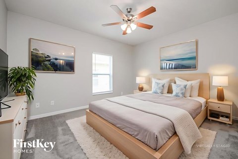 A bedroom with a bed, nightstand, and a ceiling fan.