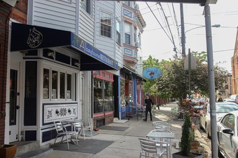 a man is walking down a sidewalk in front of a restaurant